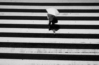 High angle view of woman walking on zebra crossing