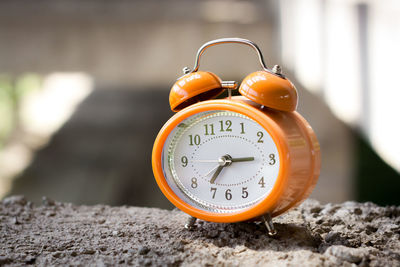 Orange vintage style alarm clock in an abandoned unfinished building.