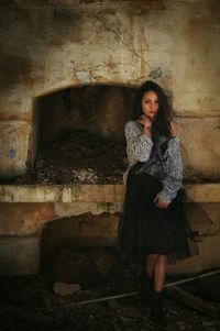 Portrait of young woman standing against wall