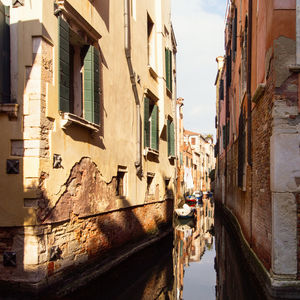 Canal amidst buildings in city against sky
