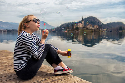 Woman sitting on pier over lake