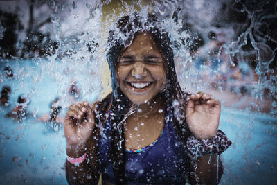 Water splashing on smiling girl in swimming pool