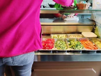 Midsection of woman standing by food in kitchen