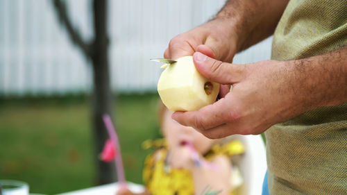 Summer, in the garden, slow motion, close-up, men's hands, peel an apple with a knife, cut the peel