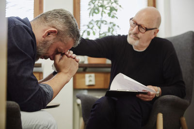 Depressed man crying while therapist consoling him at community center