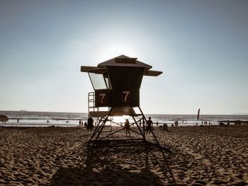 Lifeguard hut at beach against clear sky during sunset