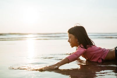 Side view of young woman sitting at beach