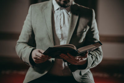 Midsection of man holding book