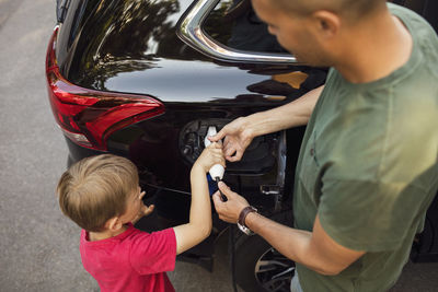 High angle view of father and son charging electric car