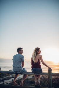 Young couple standing on beach against clear sky