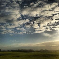 Scenic view of grassy field against cloudy sky