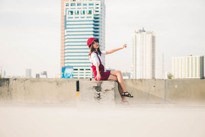 Side view of woman jumping against buildings in city