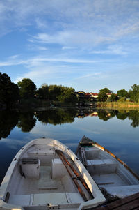 Boats moored by lake against sky