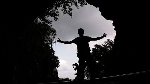 Silhouette man standing by tree against sky