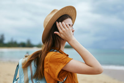 Midsection of woman wearing hat on beach