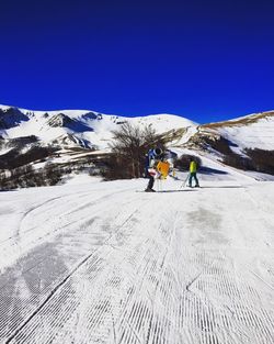 People skiing on snowcapped mountain against clear sky