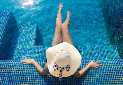 High angle view of woman wearing hat while relaxing at swimming pool