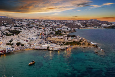 Aerial view of sea and buildings against sky during sunset