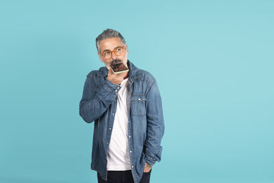 Young man standing against blue background