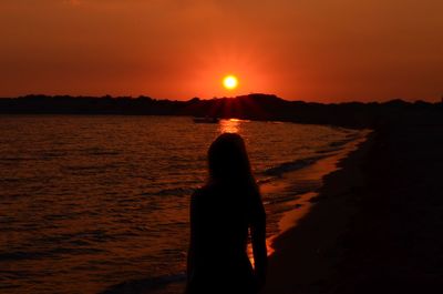 Silhouette woman standing on beach during sunset