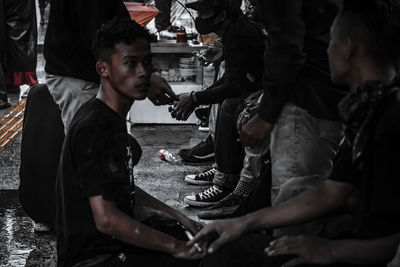 Side view of a young man sitting in city