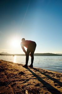 Man standing on beach against bright sun