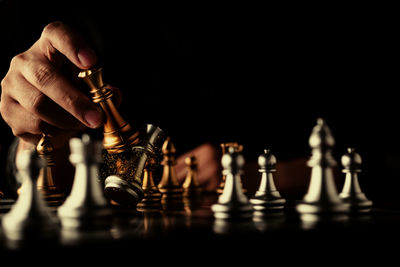 Cropped hands playing chess against black background