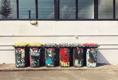 Garbage bins with graffiti on street against building