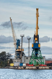 Cranes at commercial dock against sky