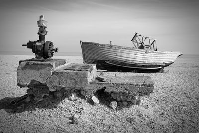 Abandoned boat moored at beach against sky