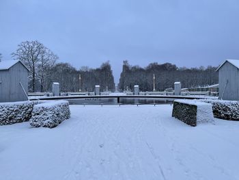 Snow covered field by building against sky