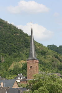 Tower amidst trees and building against sky