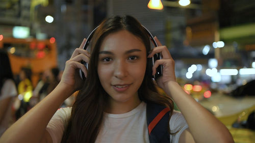 Portrait of smiling woman using mobile phone at night