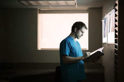Doctor writing report while standing in hospital ward