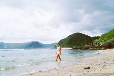 Woman wading in sea against sky