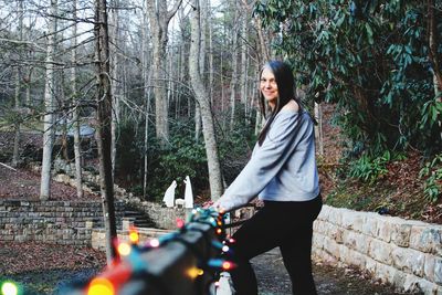 Full length of young woman riding bicycle in forest