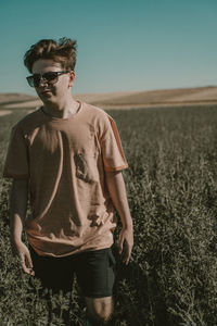 Full length of young man wearing sunglasses standing on field