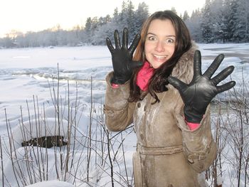 Portrait of smiling young woman standing on snow field