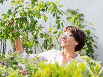 Young woman wearing sunglasses while standing against plants