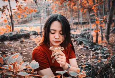 Beautiful young woman sitting on sidewalk during autumn