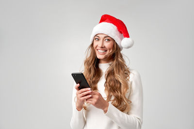 Young woman using mobile phone against white background