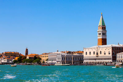 View of buildings at waterfront against blue sky