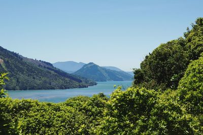 Scenic view of sea and mountains against clear blue sky