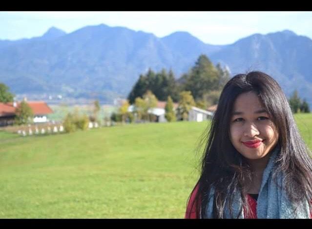 PORTRAIT OF A SMILING YOUNG WOMAN AGAINST TREES