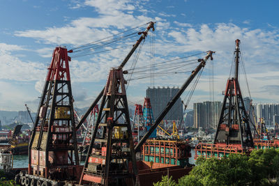 Cranes at commercial dock against sky