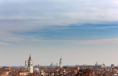 Buildings in city against cloudy sky