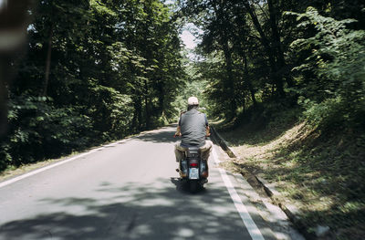 Rear view of man riding motorcycle on road