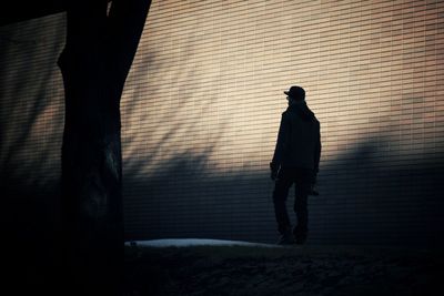 Silhouette person standing against wall