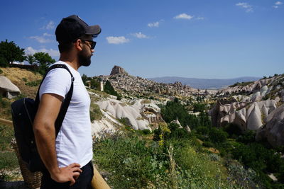 Side view of man standing on rock against sky