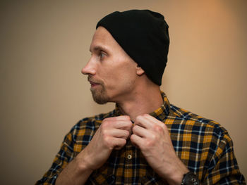 Portrait of young man looking away against gray background